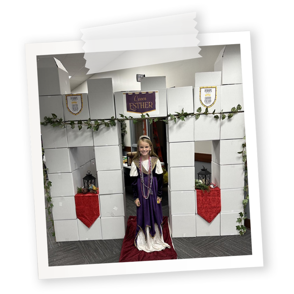 A church trunk-or-treat booth for the book of Esther. Little girl standing in front of a castle made out of boxes.