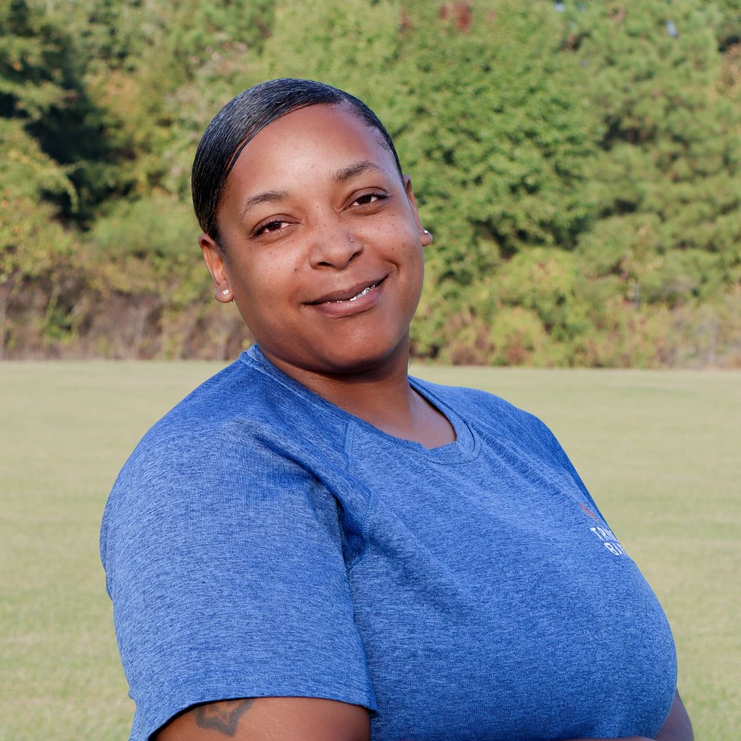 Custodian Gia Webster standing in front of trees